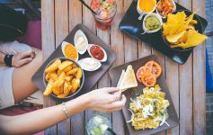 Girl picking up toast from a table spread with vegetarian Mexican food