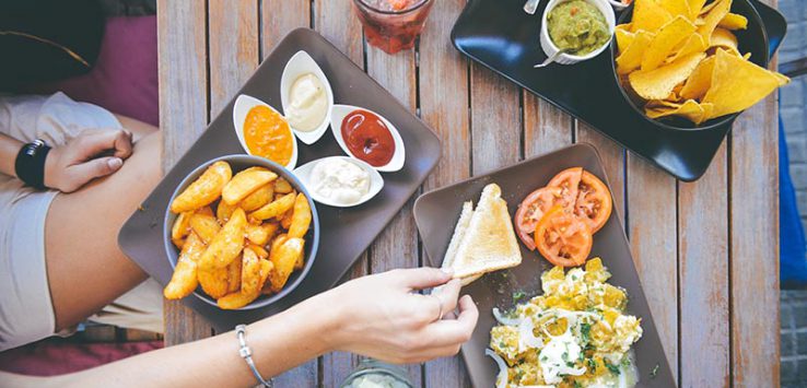 Girl picking up toast from a table spread with vegetarian Mexican food