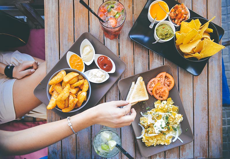 Girl picking up toast from a table spread with vegetarian Mexican food