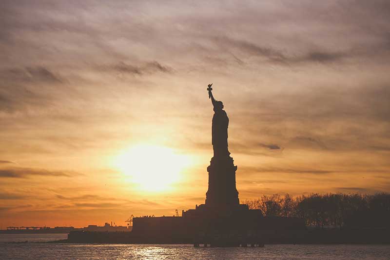 Statue of Liberty silhouetted against a sunrise 