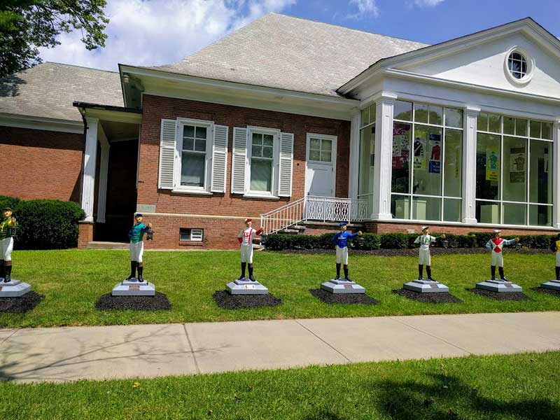 Jockey statues lining the sidewalk outside of the National Racing Museum in Saratoga Springs NY