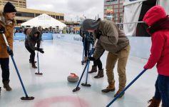 A family learning the sport of curling on an ice rink