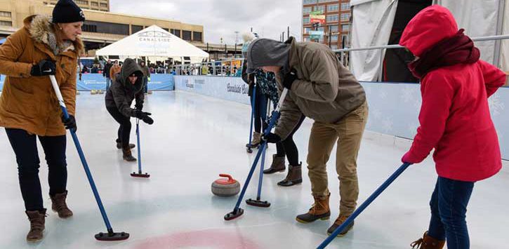 A family learning the sport of curling on an ice rink