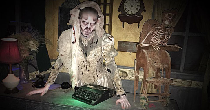 creepy white and gray creature standing over a keyboard ona  desk, skeleton next to him